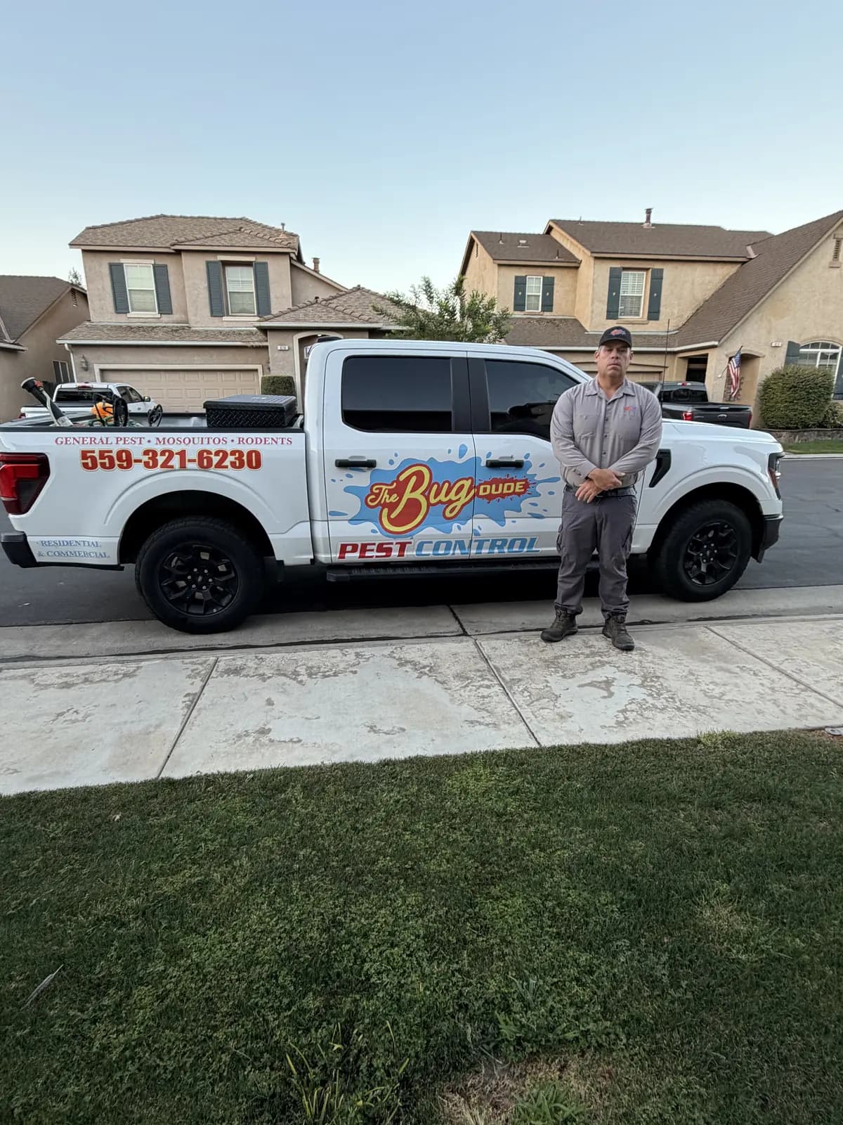 The Bug Dude standing beside the branded pest-control truck on a residential street